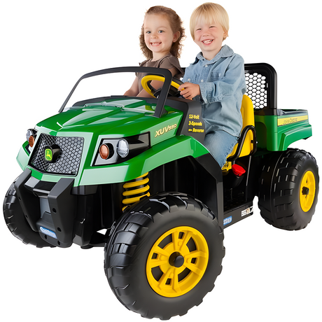 Two smiling children sitting in a green ride-on John Deere XUV toy vehicle, featuring large yellow wheels and realistic detailing, including headlights and a roll bar