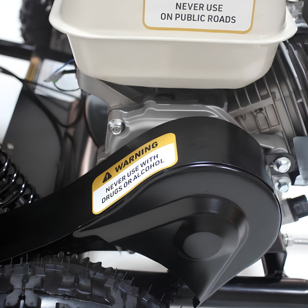 Close-up of a black protective guard with a yellow warning label that reads 'WARNING NEVER USE WITH DRUGS OR ALCOHOL!' attached to a small engine with a cream-colored fuel tank.