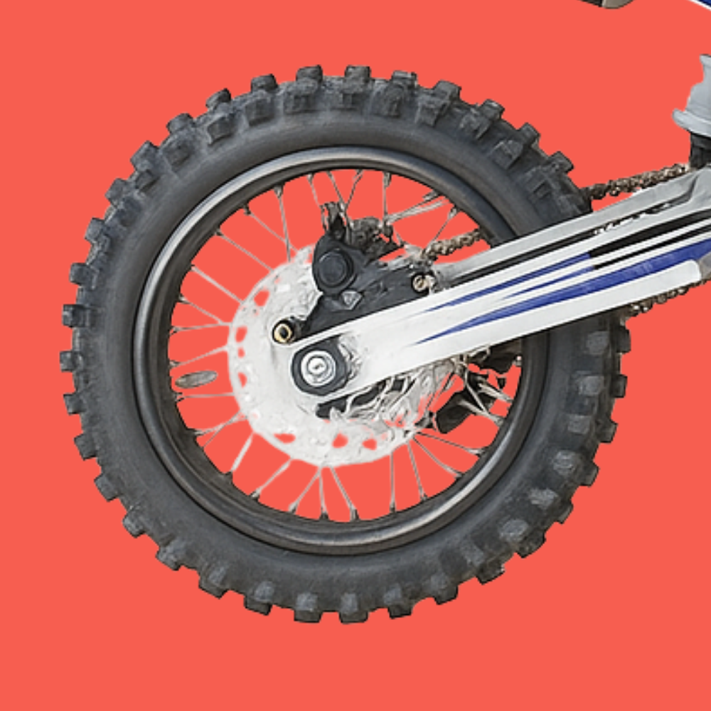 Close-up of the GMX dirt bike’s knobby rear tyre, showcasing tread pattern and chain assembly.