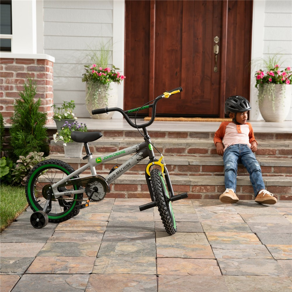 Child sitting on steps next to a bicycle in front of a house entrance.