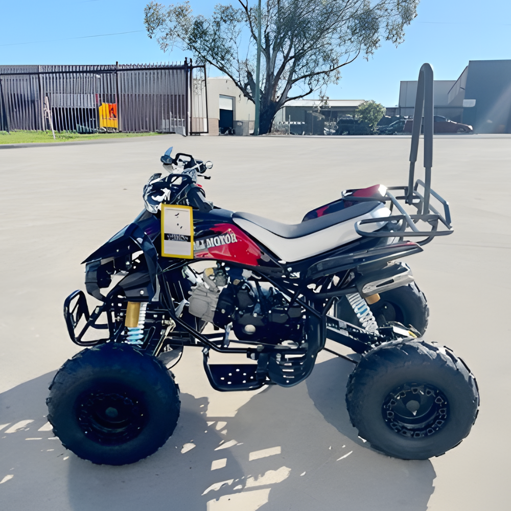 Four-wheeler parked on a concrete surface with a building and tree in the background