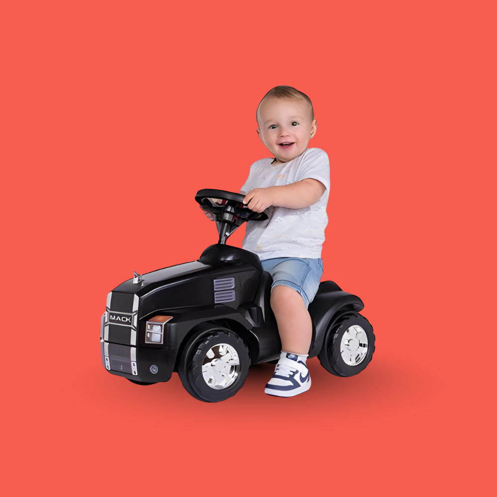 Child sitting on a toy truck against an orange background