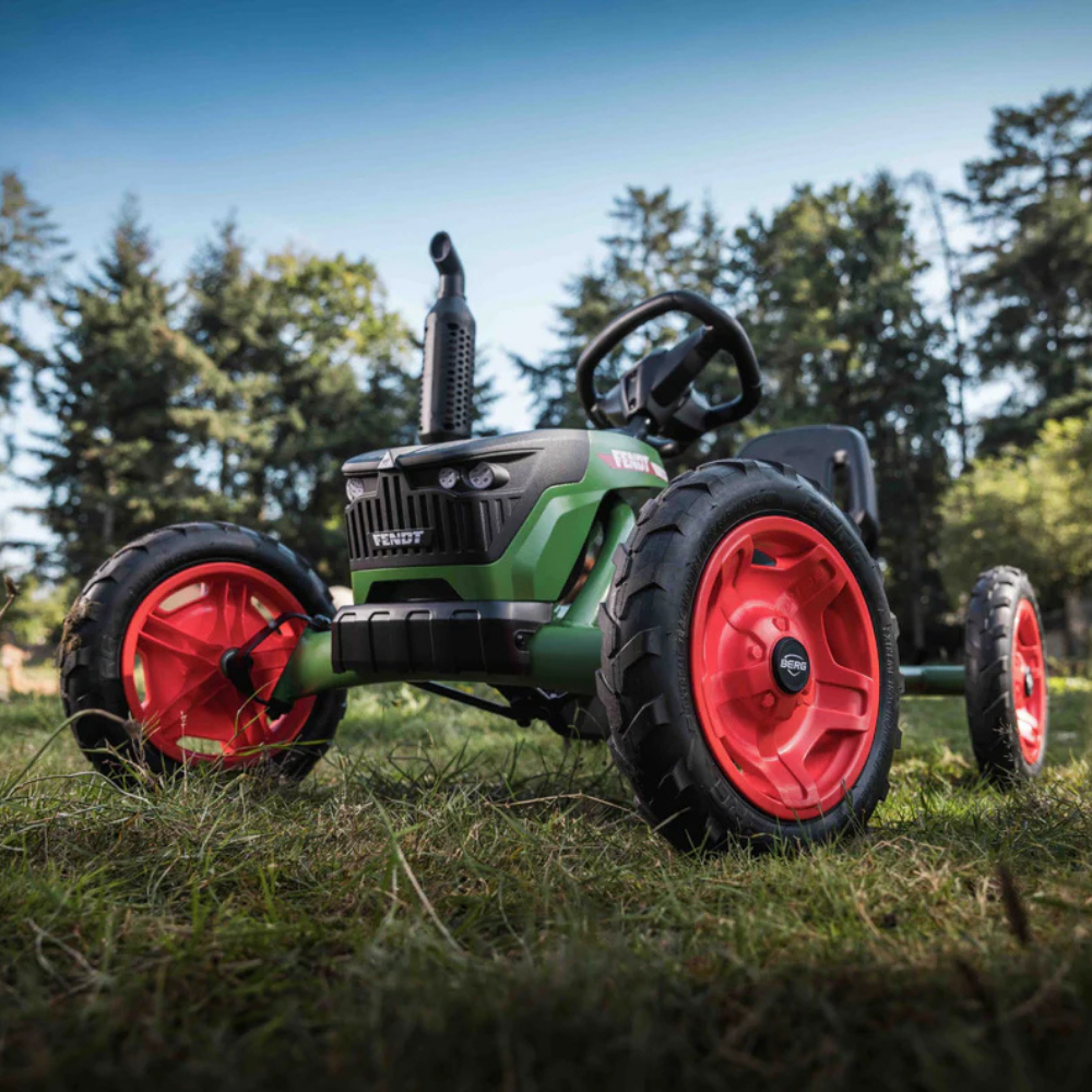 Children's toy tractor with red wheels on grass