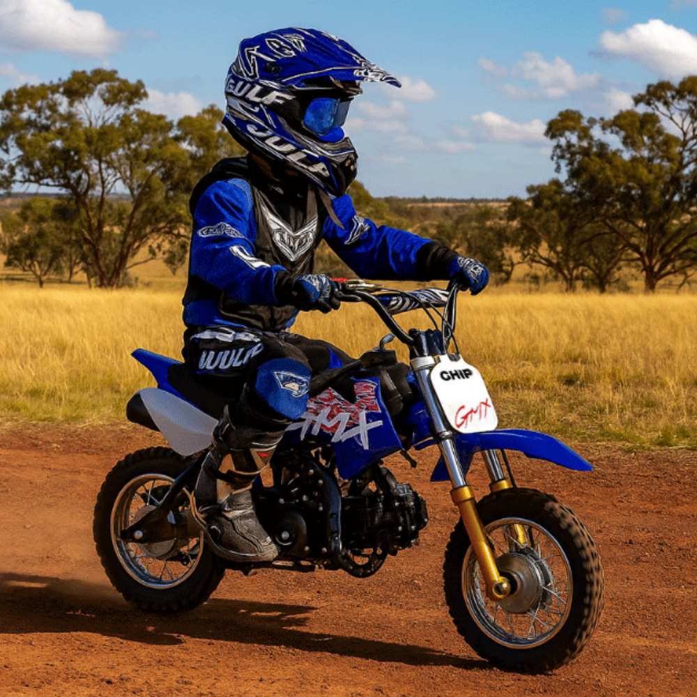 Action shot of a child riding the blue GMX dirt bike on a dirt trail, wearing a full-face helmet and riding gear.