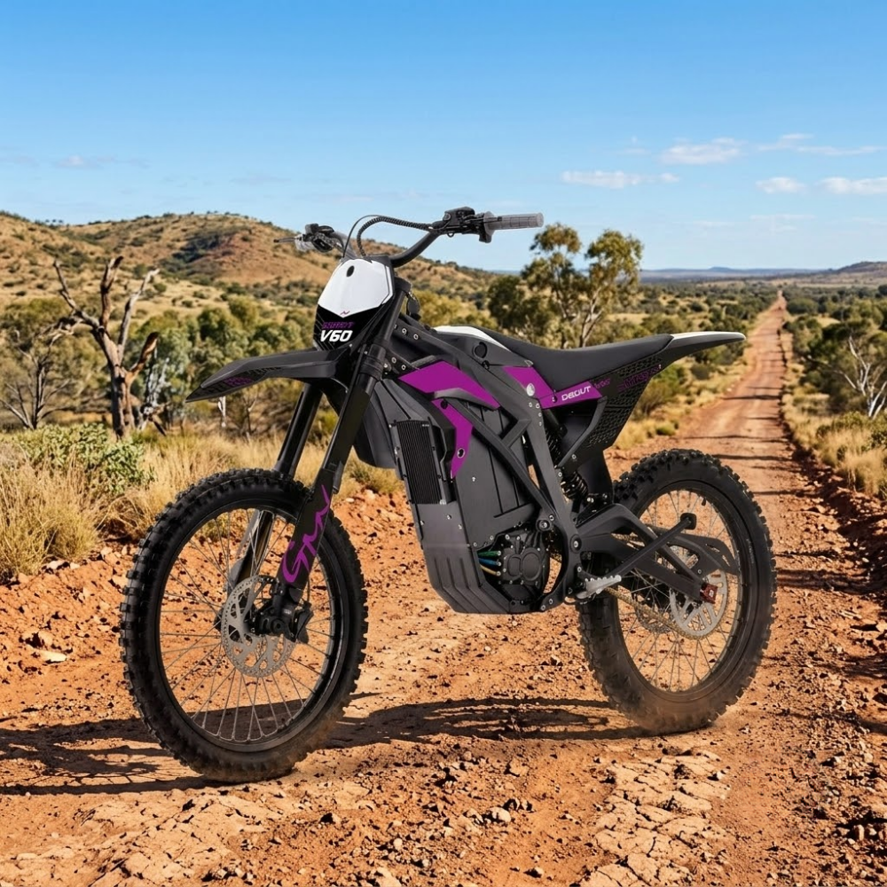 A VEDO electric dirt bike with black and purple body panels is parked on a dirt road in an outdoor desert landscape under a blue sky.