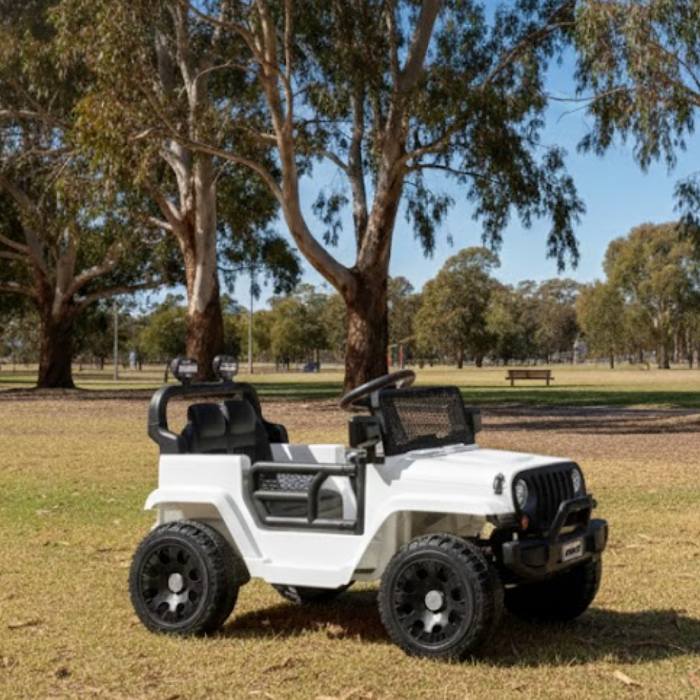 White toy jeep on grass with trees in the background