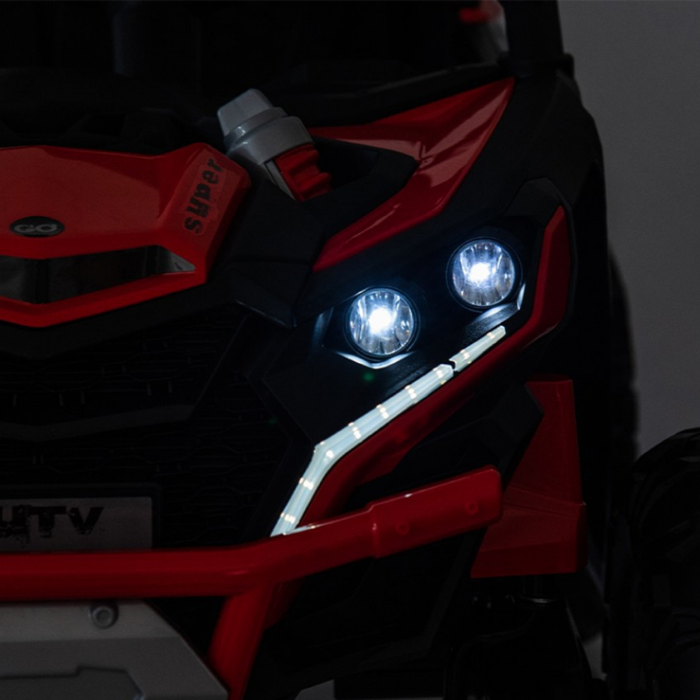 Close-up of a red and black off-road vehicle with illuminated headlights on a dark background.