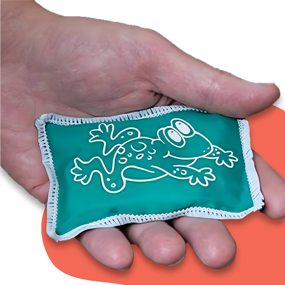 A close-up of a hand holding a green beanbag featuring a white frog illustration. The beanbag is displayed against a white and red background