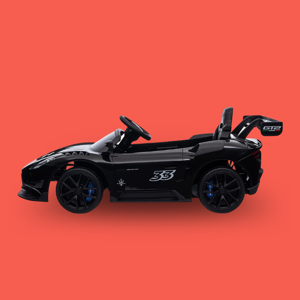 A black toy sports car with blue brake accents and a large rear spoiler, shown in profile against a solid coral-red background.