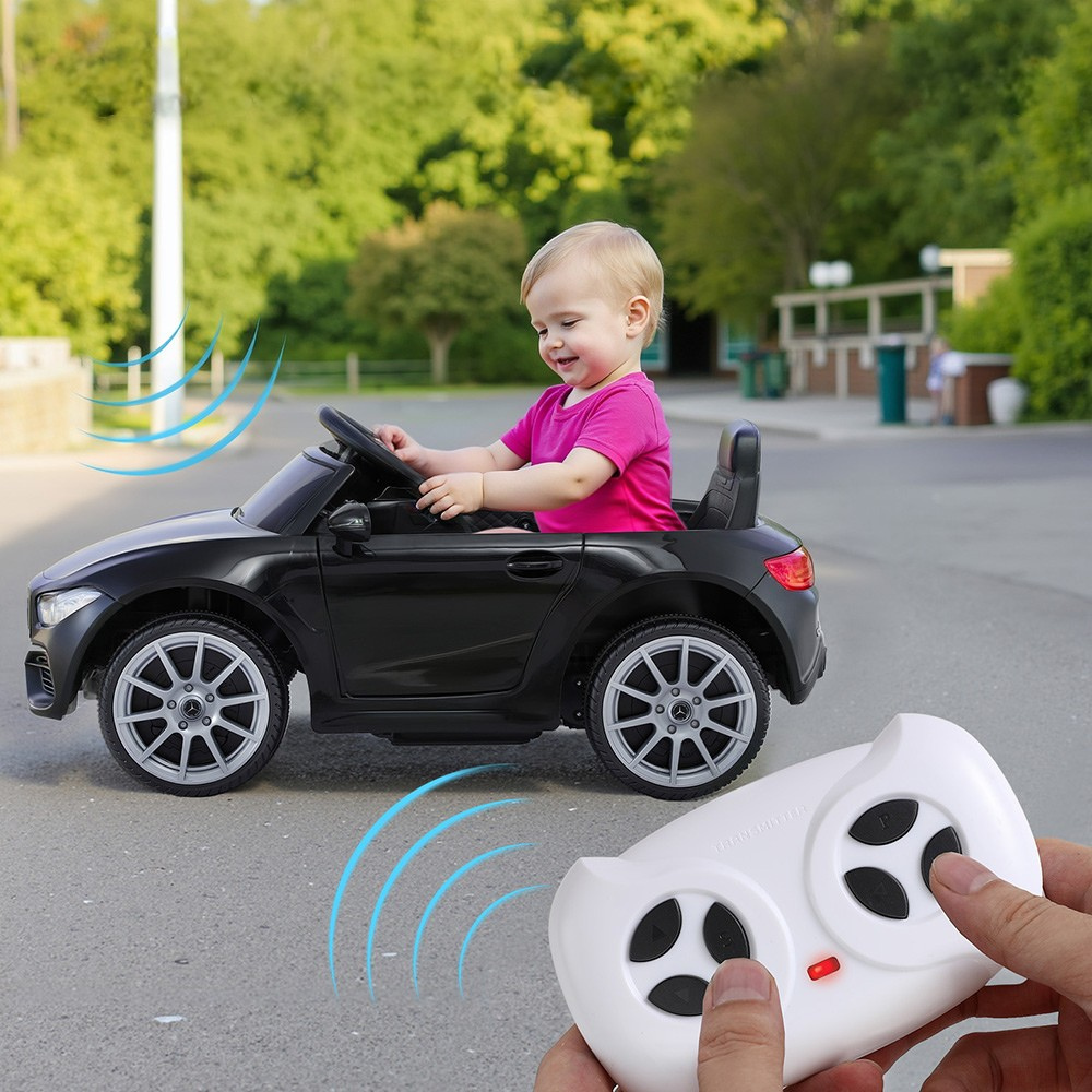 Child playing with a toy car and remote control outdoors.