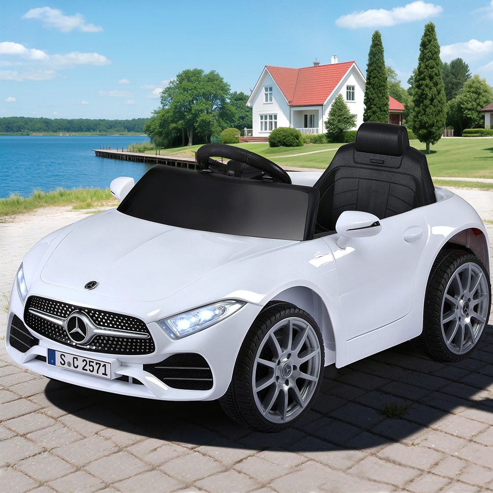 White toy car with Mercedes-Benz logo on a paved area near a house and lake.