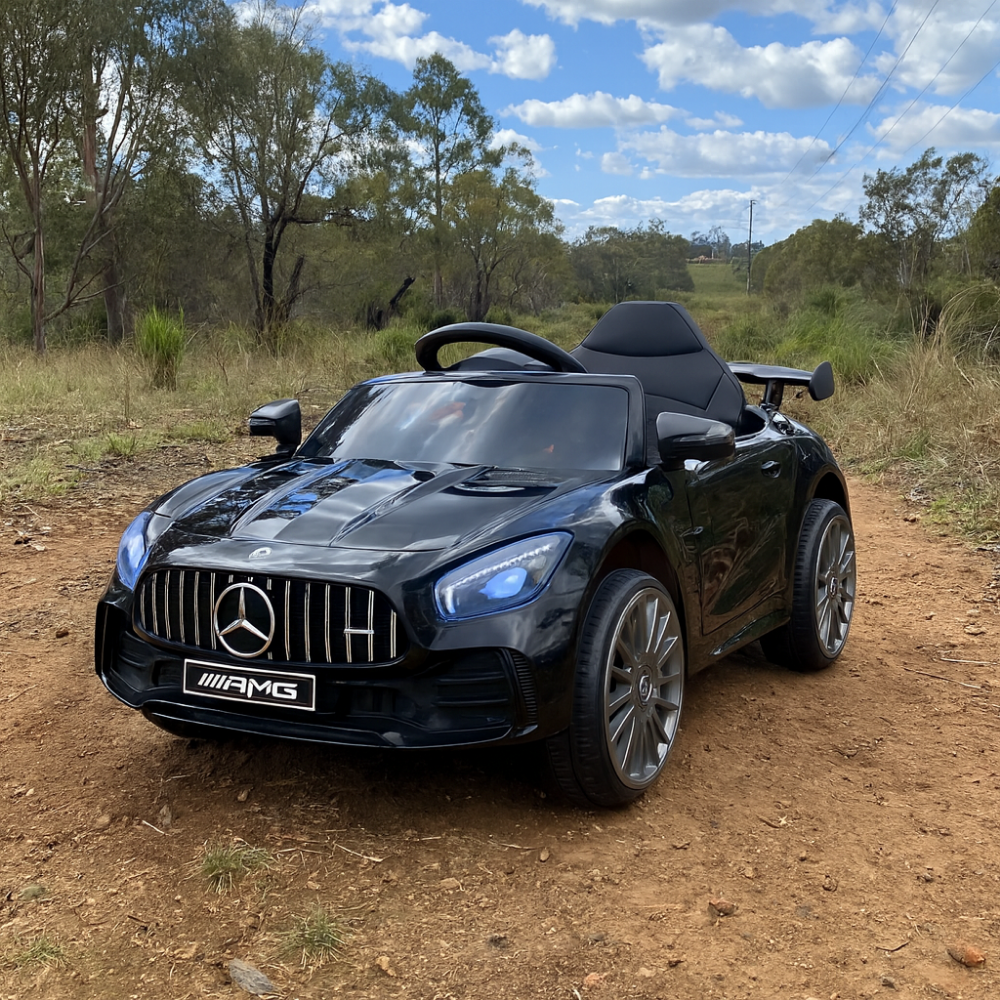 Black Mercedes-Benz AMG toy car on a dirt road with trees and blue sky in the background