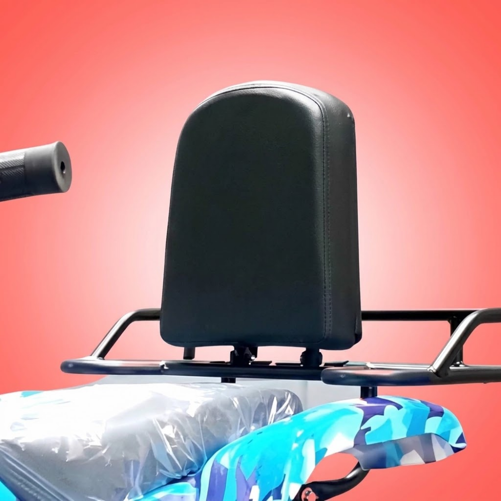 A close-up of a black padded backrest or seat component mounted on a metal frame, with part of a blue-and-white patterned cushion visible below, against a solid pink background.