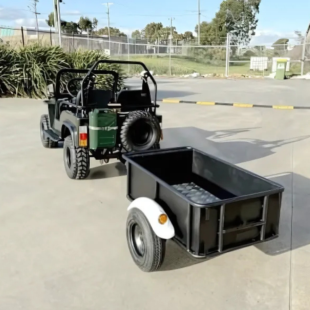 Small green utility vehicle with a black trailer attached on a paved surface.