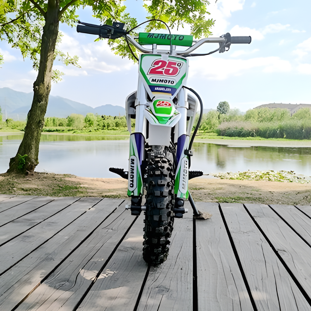 Children's dirt bike on a wooden deck with a scenic background of trees and water.
