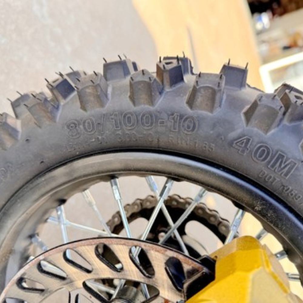 Close-up of a motorcycle tire with tread pattern and rim details.