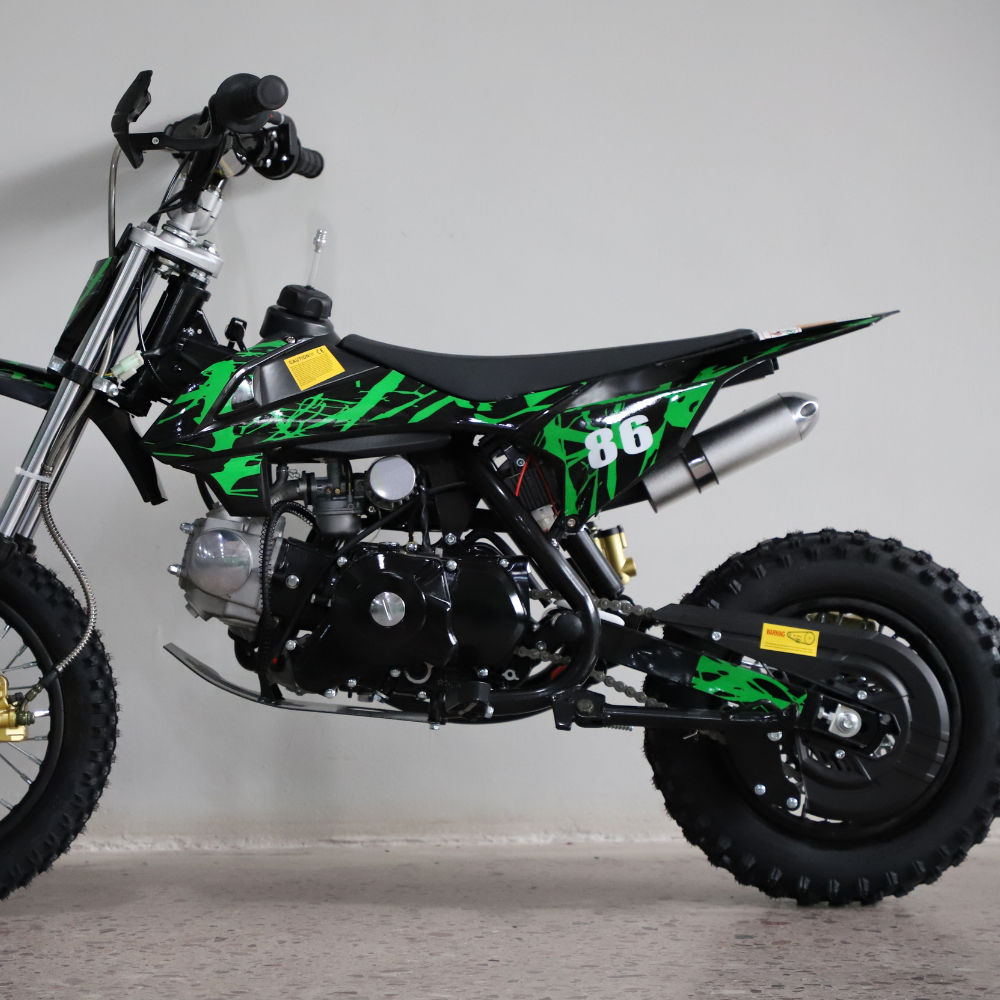 Rear-angled studio shot of the dirt bike, focusing on rear tyre, chain, and exhaust.