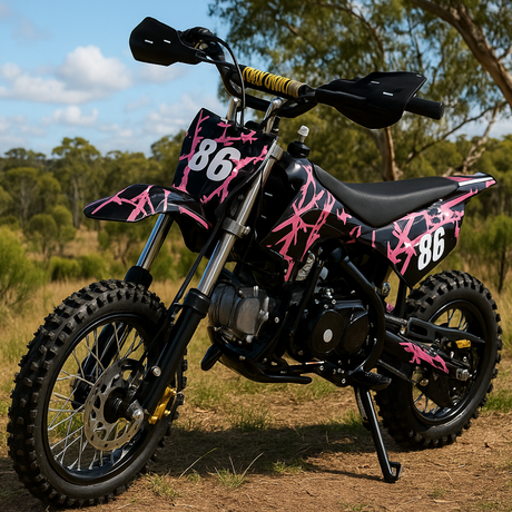 Outdoor shot of pink and black dirt bike on dirt terrain with trees in the background, positioned front-left to show tread and stance.