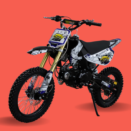 Front angled view of a white and black kids’ dirt bike with gold front forks and bold graphics, set against a red backdrop.