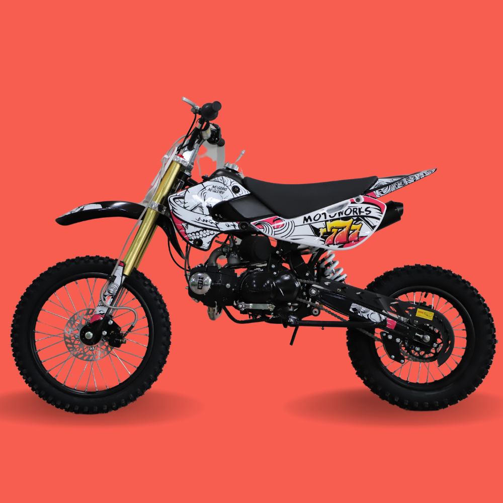 Left-side profile of a kids’ dirt bike with red and white #77 decals, gold front forks, and off-road tyres on a red background.
