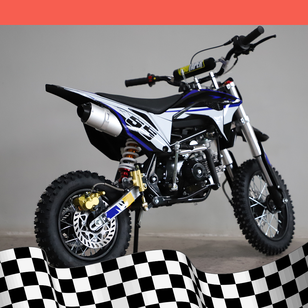 A full right-side view of the dirt bike, highlighting the frame and exhaust system against a checkered base background