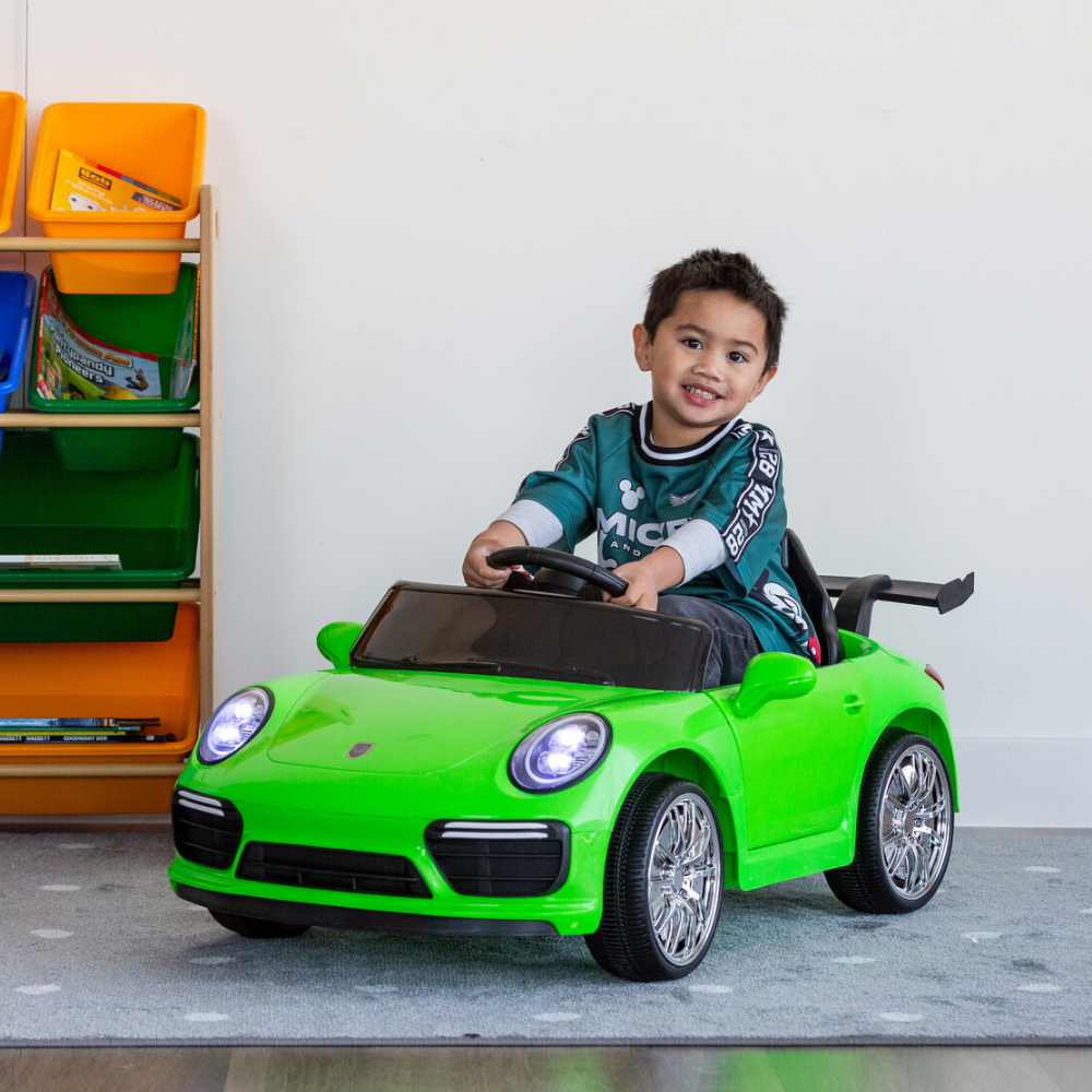 Child sitting in a green toy car with colorful storage bins in the background