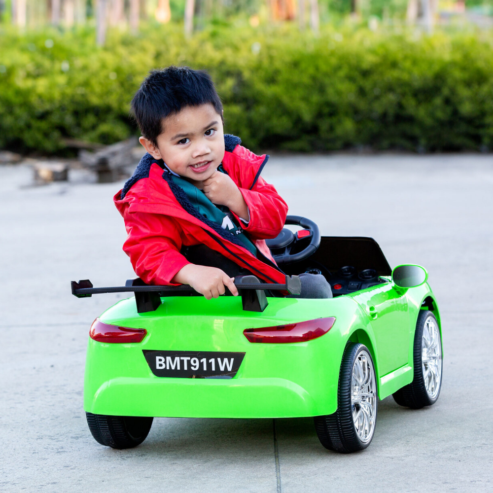 Child sitting in a green toy car outdoors
