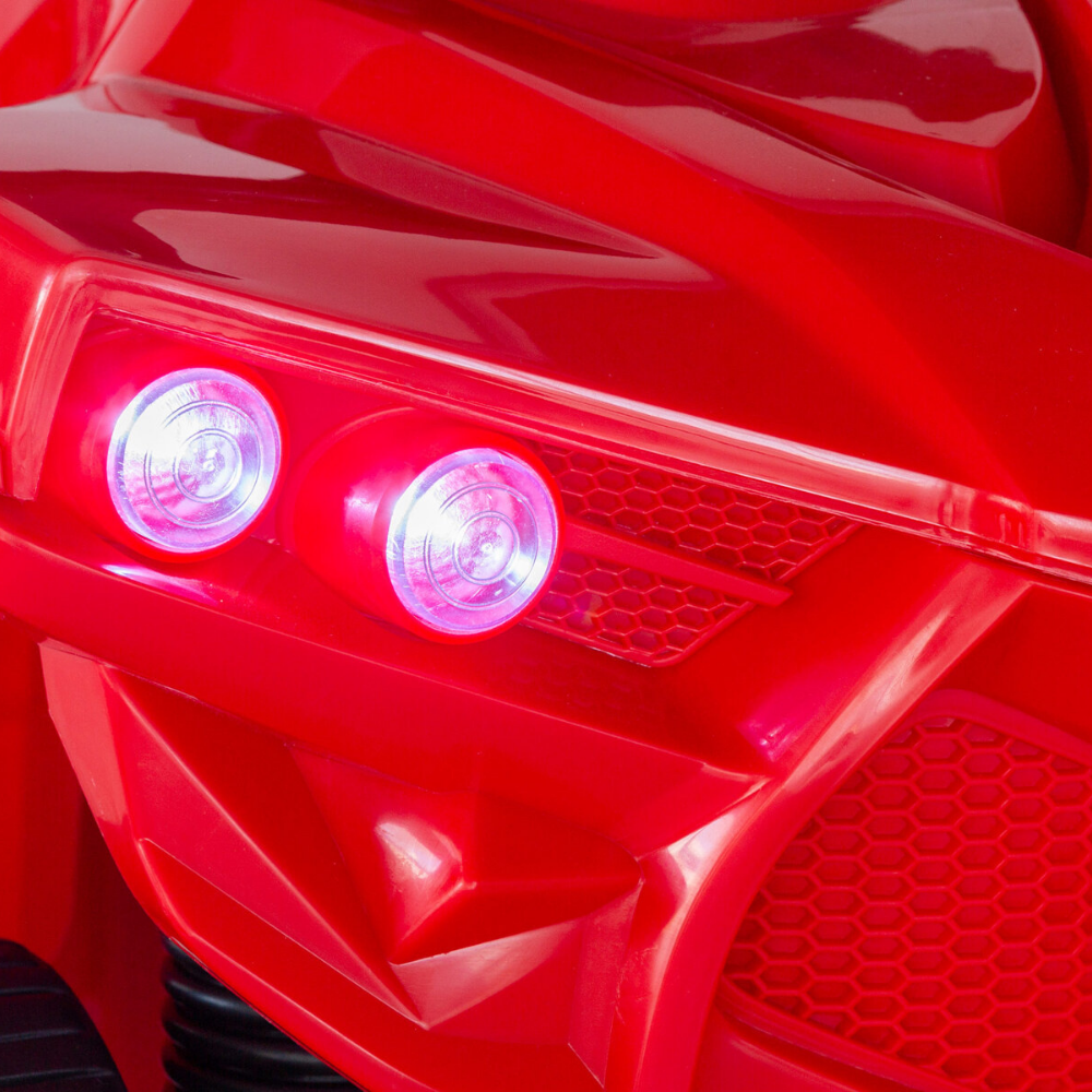 Close-up of a red vehicle's front grille with illuminated lights.