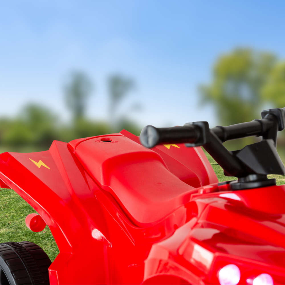 Red toy lawn mower on grass with a blurred green background