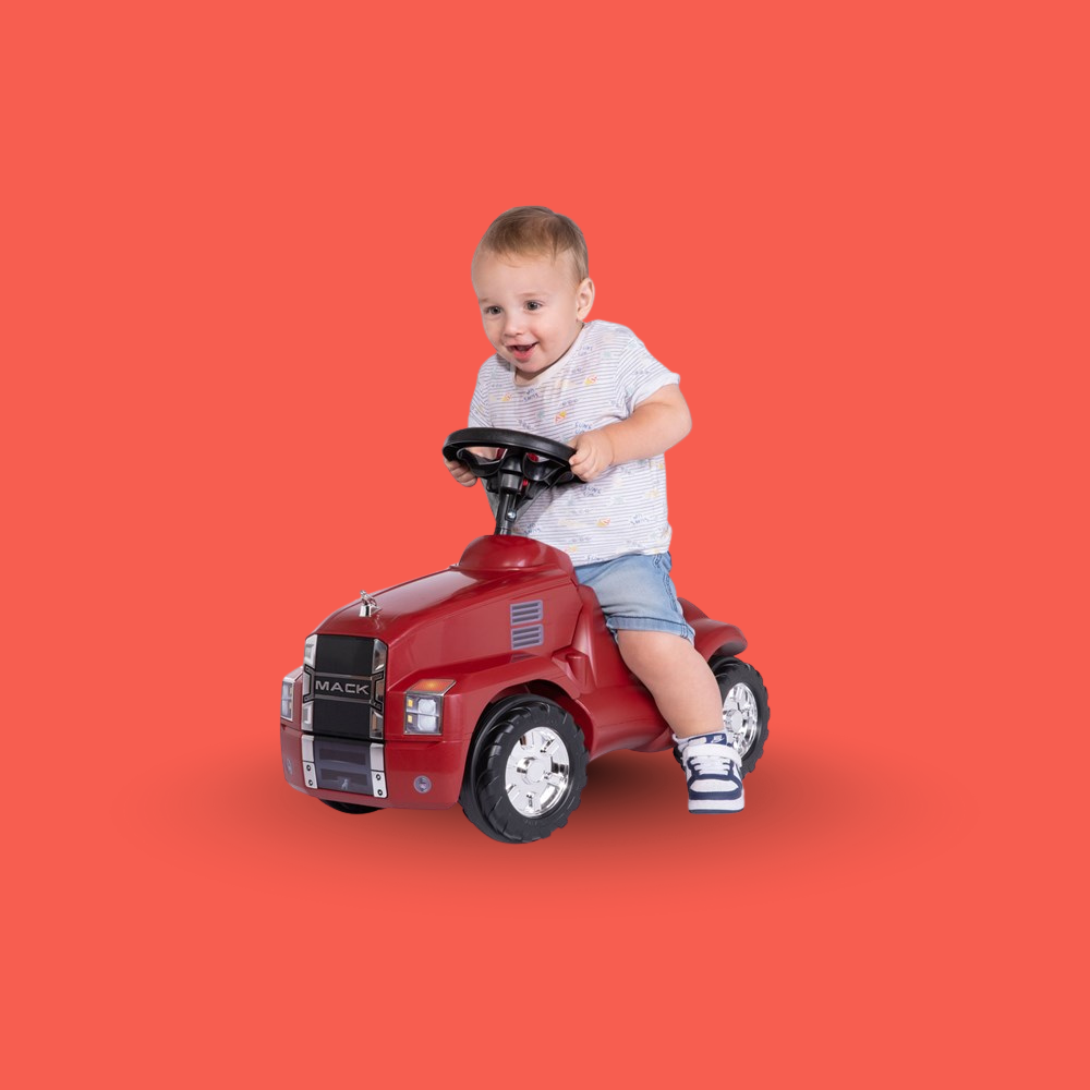 Child sitting on a red toy truck against an orange background