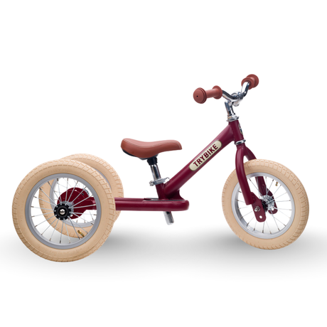 Red balance bike with beige tires on a white background