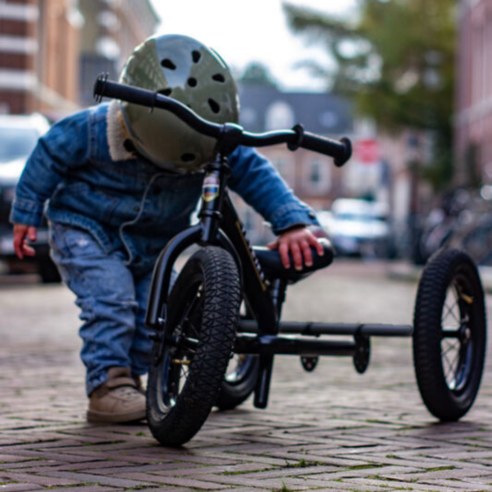 Child on a tricycle with a helmet in an urban setting
