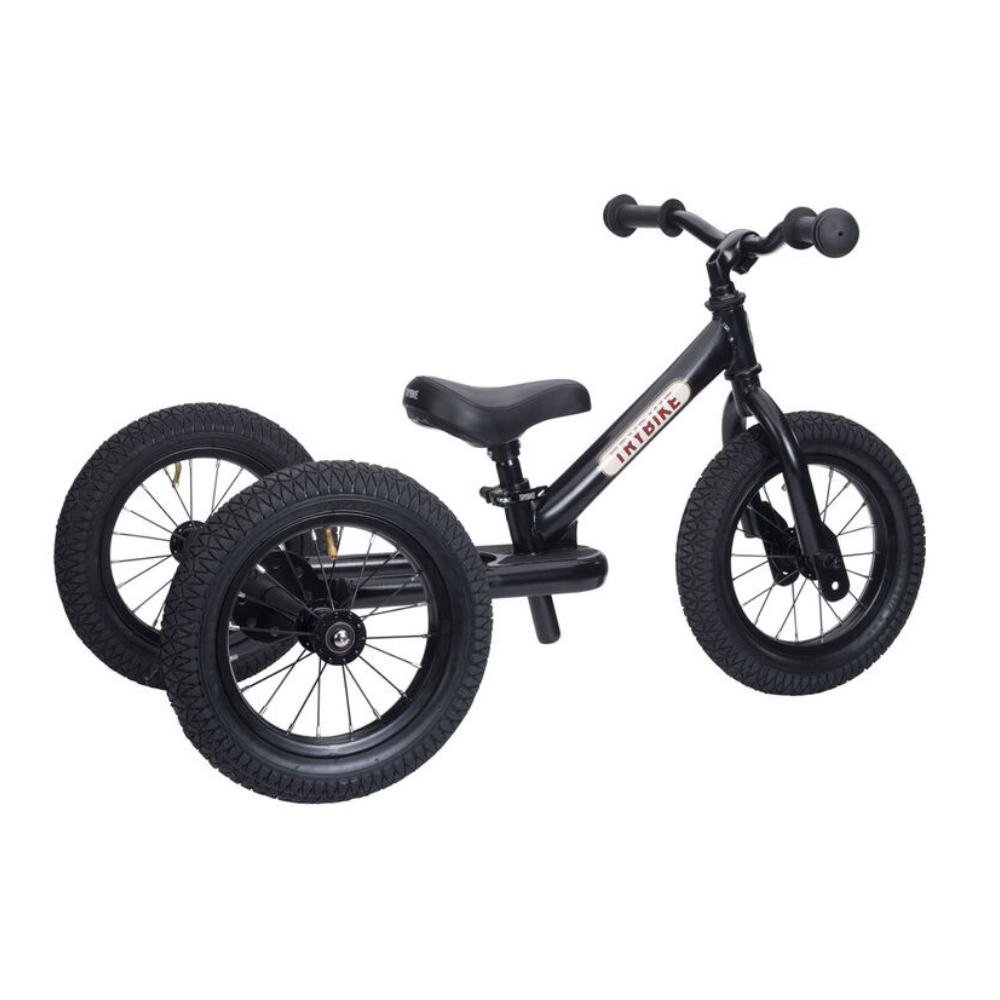 Black balance bike with training wheels on a white background
