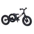 Black balance bike with training wheels on a white background