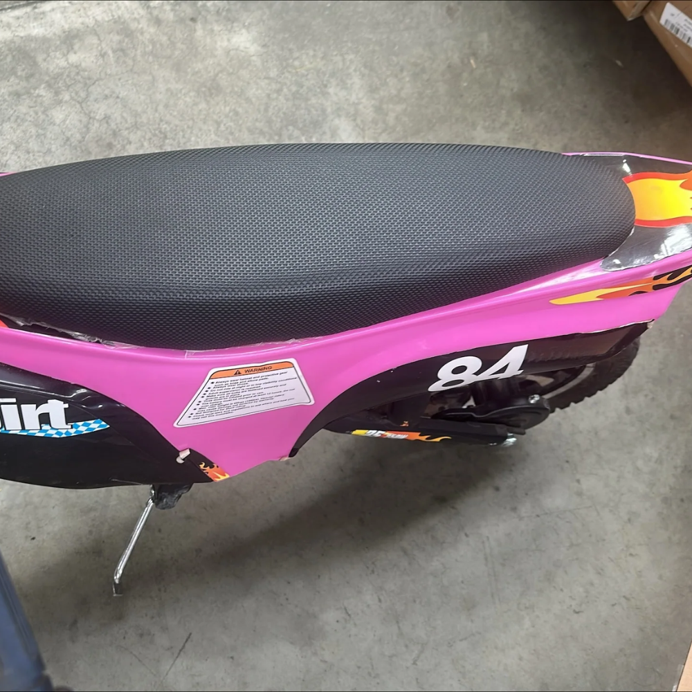 Top view of pink kids dirt bike showing full black seat with tear near the front and warning label on frame.