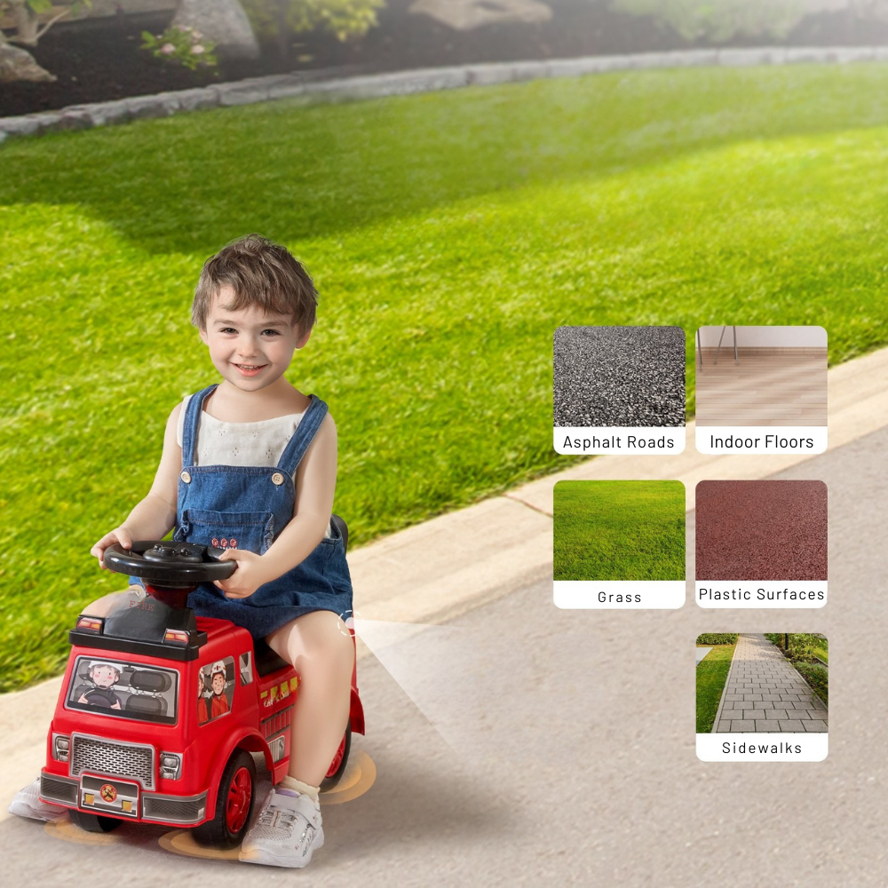 Child playing with a red toy fire truck on a sidewalk with grass and pavement in the background