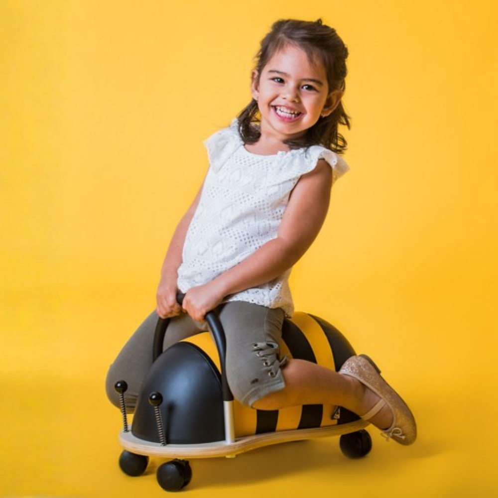 Child riding a toy horse on a yellow background