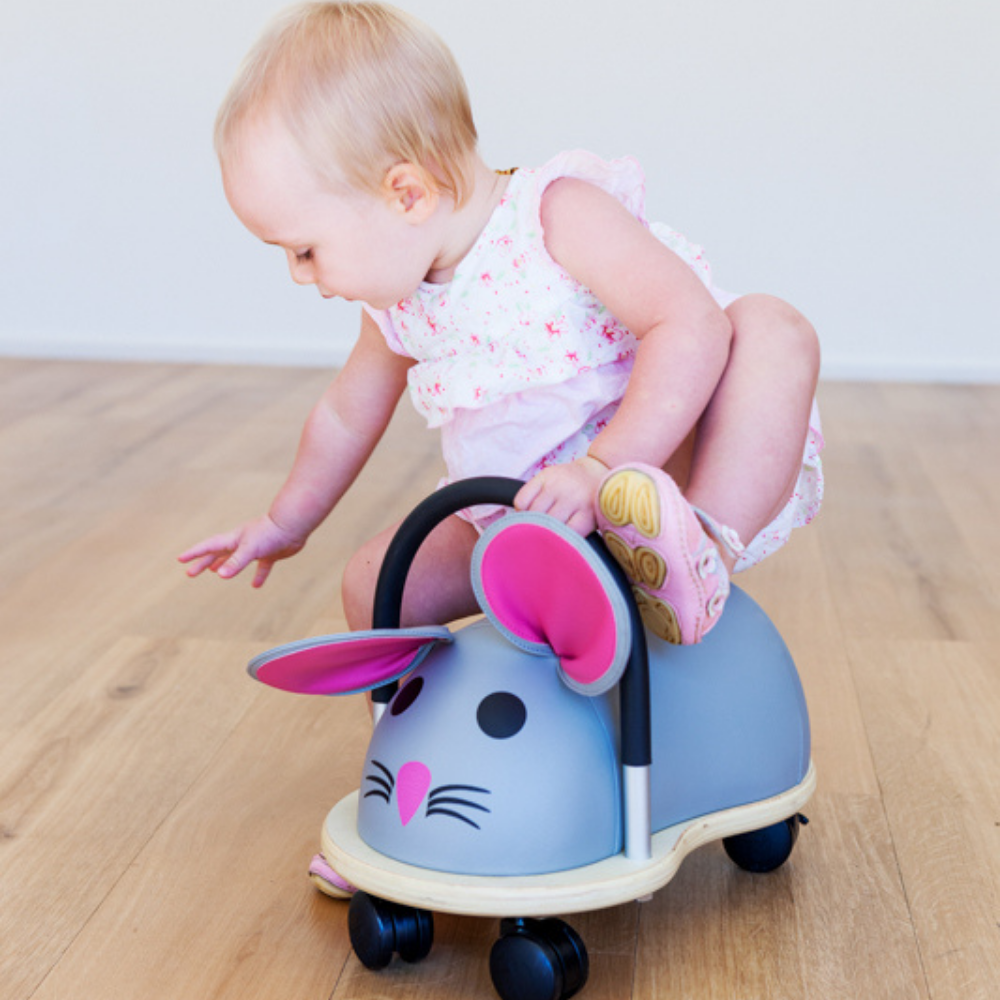 Child playing with a toy car shaped like a rabbit on a wooden floor.