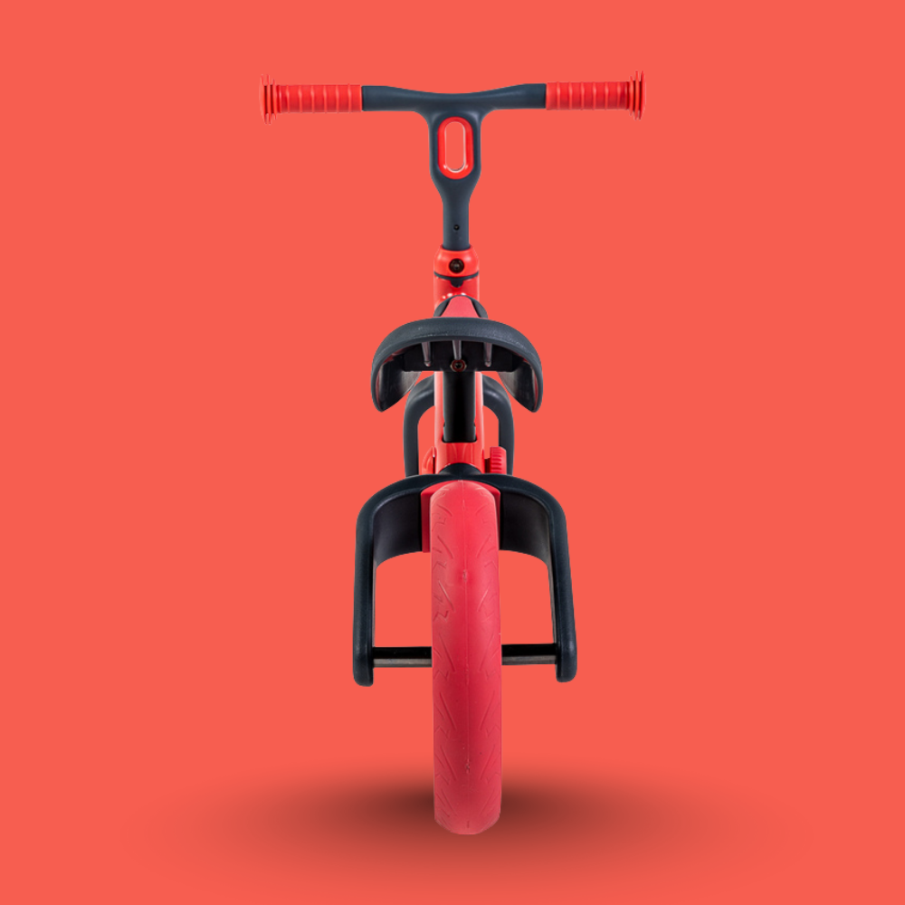 Red balance bike with black handlebar and seat on a red background