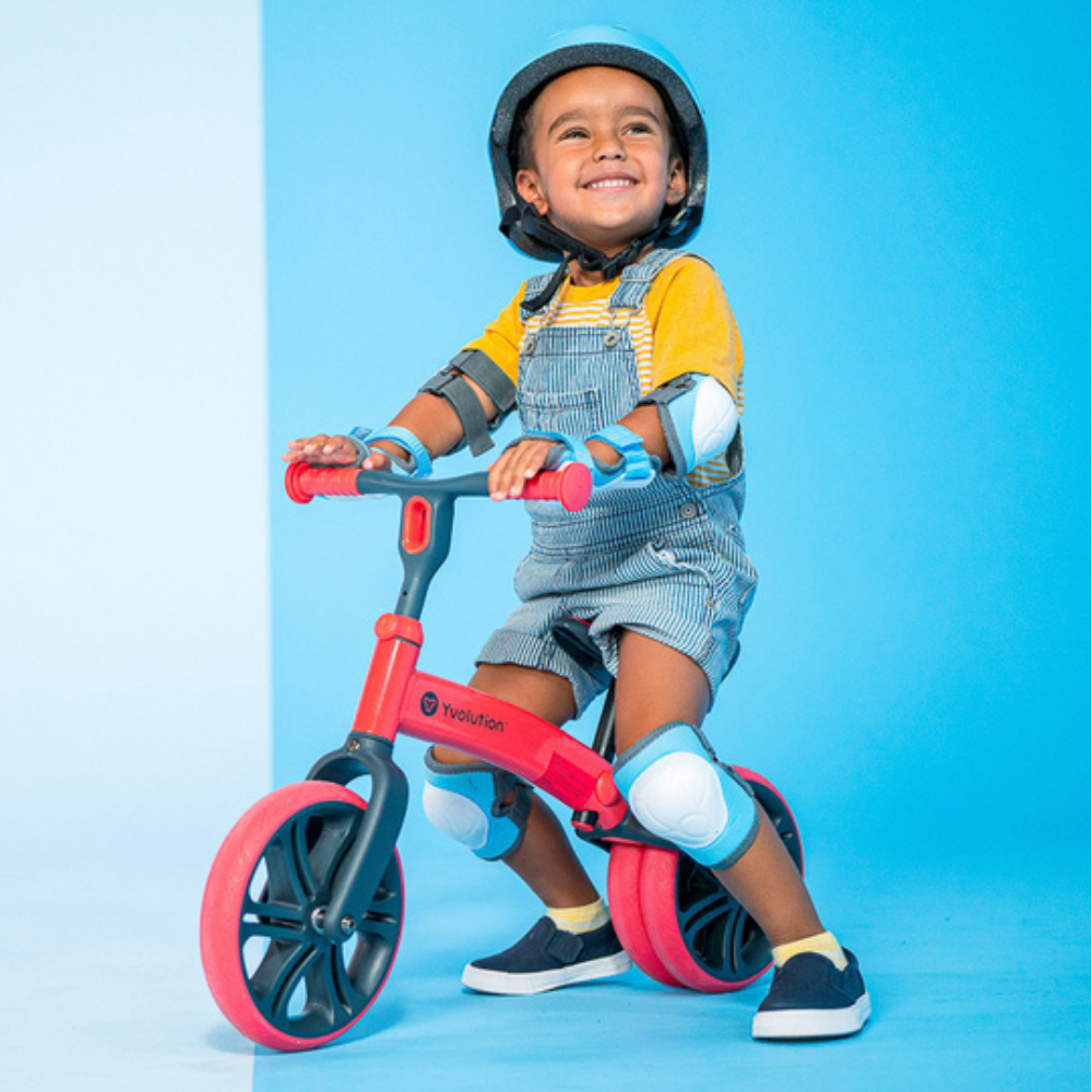 Child riding a red balance bike against a blue background