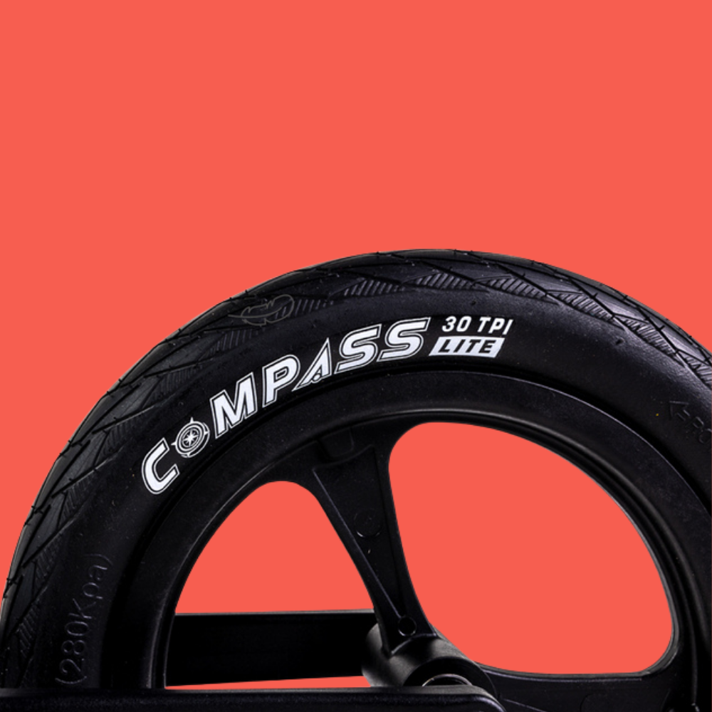 Black tire with 'Compass' branding on a red background