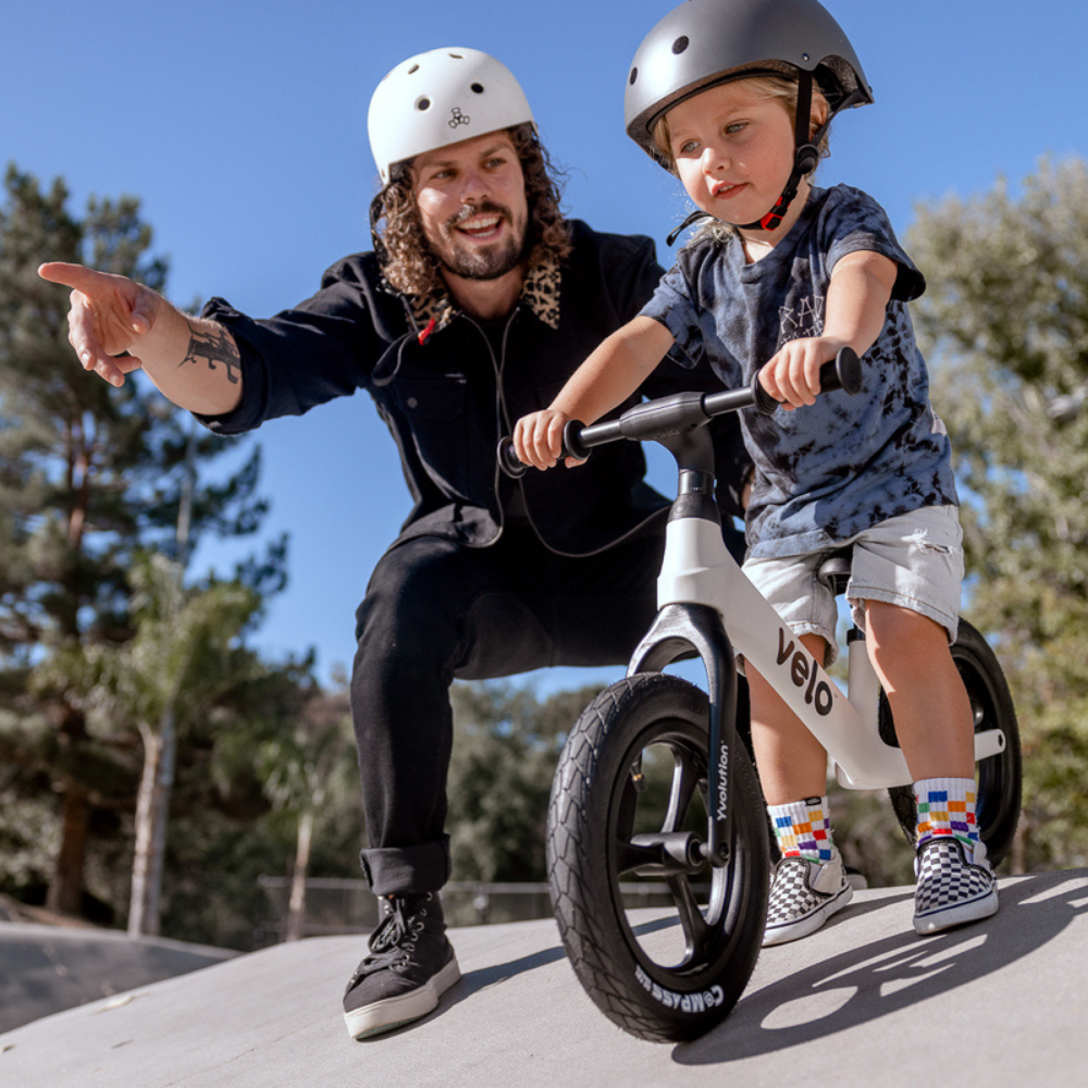 Man and child on a balance bike with trees in the background