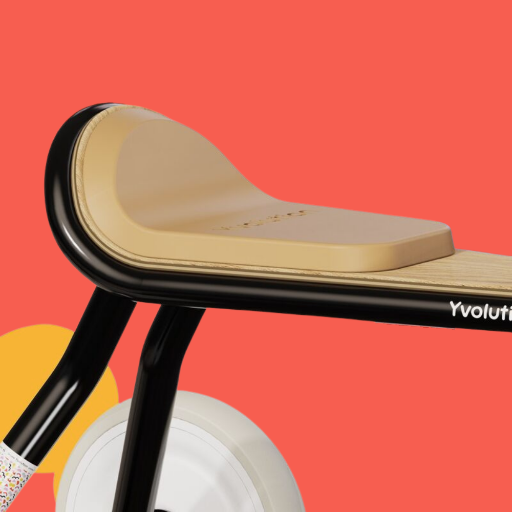 Children's balance bike with beige seat and black frame on a red background