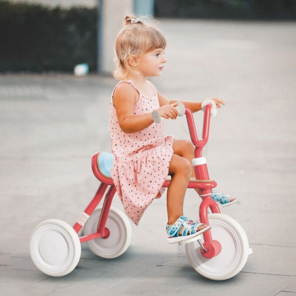 Child riding a red tricycle on a sidewalk