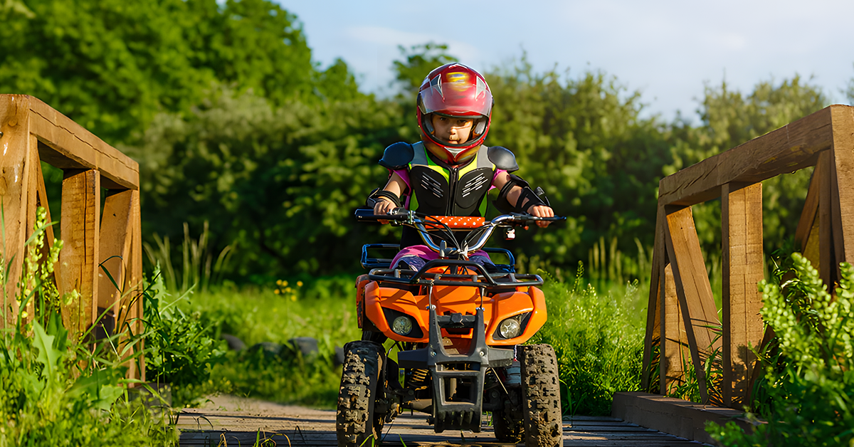 A boy riding a quad bike wearing helmet and safety gears 
