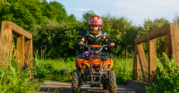A boy riding a quad bike wearing helmet and safety gears