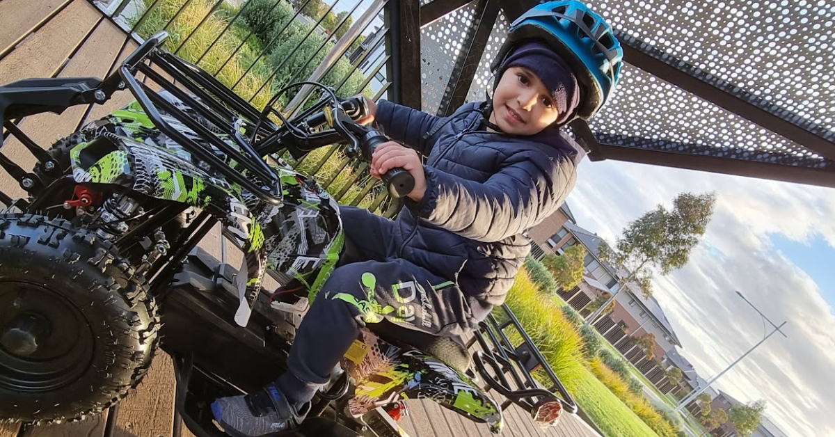 a boy riding a quadbike on a gravel surface