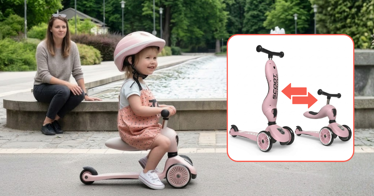 A smiling child wearing a pink helmet rides a pink three-wheel seated scooter along a paved path, while an adult watches from beside a fountain.