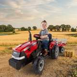 Child sitting on a red toy tractor in a field with a scenic background