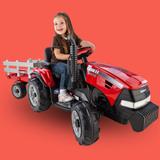 Child sitting on a red toy tractor against a red background